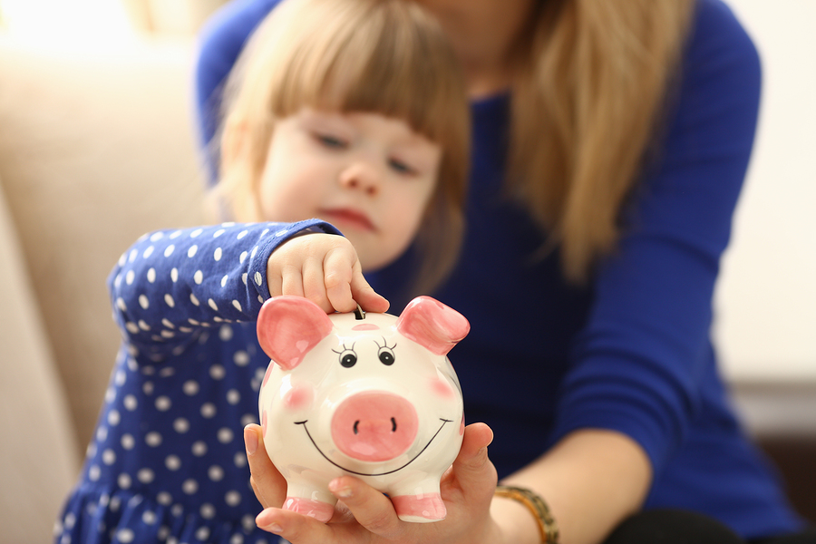 A little girl putting money in her piggy bank to symbolize an educational trust.